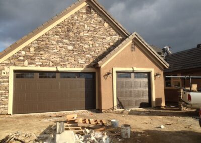 A professional is fitting a garage door onto a house
